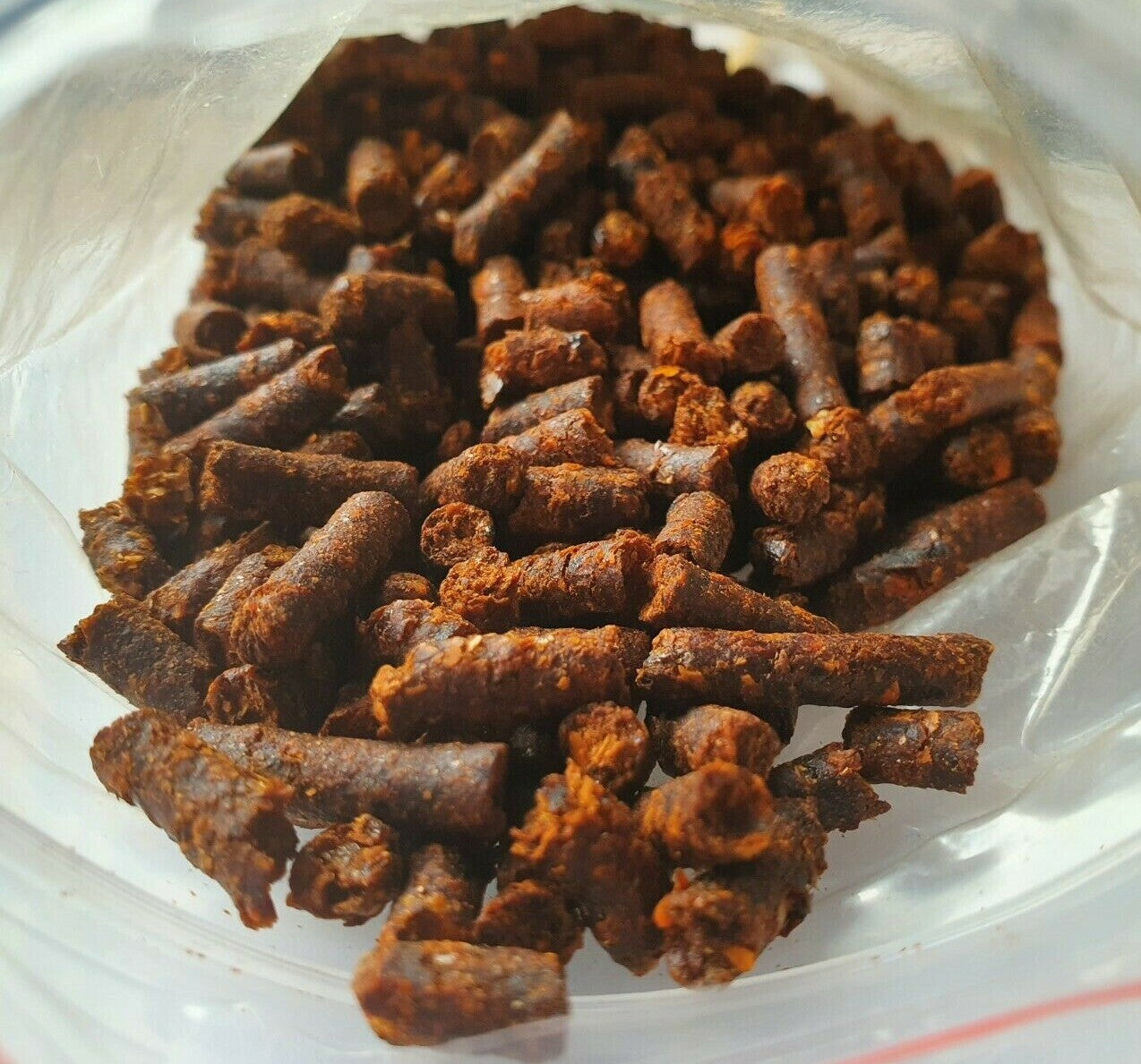 Paprika Futter Sticks für Garnelen und Krebse, 25g, von catappa-leaves, zeigt die Futtersticks in einer Schale mit Garnelen.
